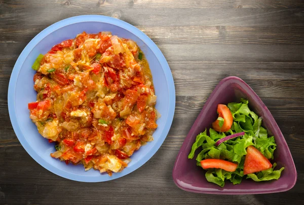 Haşlanmış domates soğan bir plaka üzerinde bir ahşap arka plan ile. haşlanmış domates soğan en iyi manzaralı. Vejetaryen Gıda