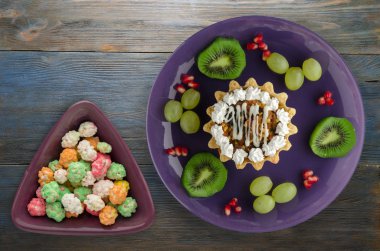 tatlı kek ve meyve (üzüm, kivi, nar) ahşap arka plan üzerinde. tatlı bir plaka Üstten Görünüm