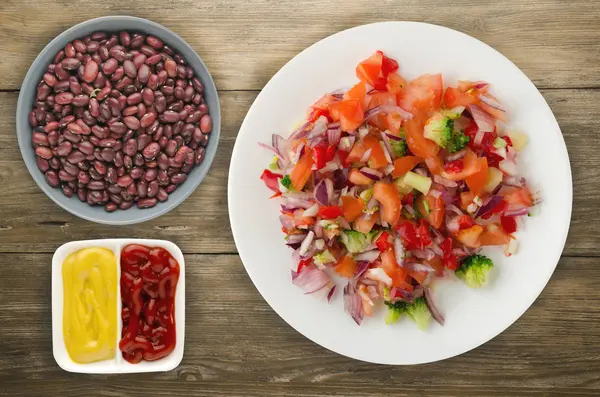 vegan gıda. salata bir tabakta sebze (biber, domates, soğan, brokoli) üzerinden. vegan salata ahşap arka plan üzerinde