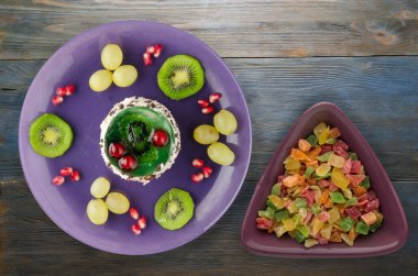 tatlı kek ve meyve (üzüm, kivi, nar) ahşap arka plan üzerinde. tatlı bir plaka Üstten Görünüm