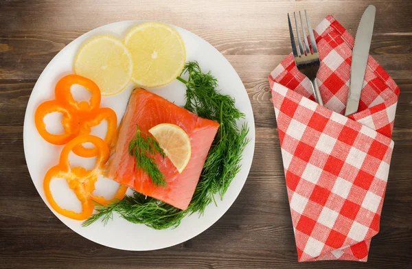 red fish trout fillets on a plate. fish trout on a wooden background. trout with dill, lemon and pepper