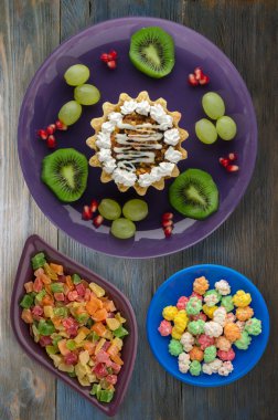 tatlı kek ve meyve (üzüm, kivi, nar) ahşap arka plan üzerinde. tatlı bir plaka Üstten Görünüm