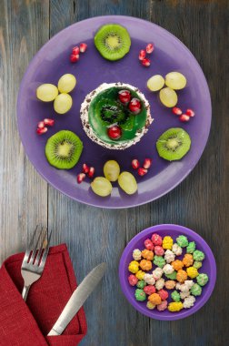 tatlı kek ve meyve (üzüm, kivi, nar) ahşap arka plan üzerinde. tatlı bir plaka Üstten Görünüm