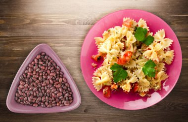 makarna bir tabak üzerine. makarna domates, soğan, lahana ahşap arka plan üzerinde