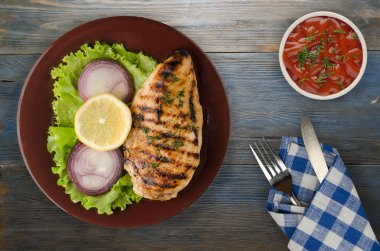  ahşap arka plan üzerinde (limon, salata, soğan) sebzeli ızgara tavuk fileto. bir plaka üstten görünüm üzerinde ızgara tavuk fileto