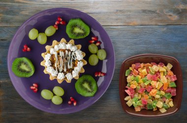 tatlı kek ve meyve (üzüm, kivi, nar) ahşap arka plan üzerinde. tatlı bir plaka Üstten Görünüm