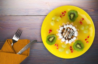 tatlı kek ve meyve (üzüm, kivi, nar) ahşap arka plan üzerinde. tatlı bir plaka Üstten Görünüm