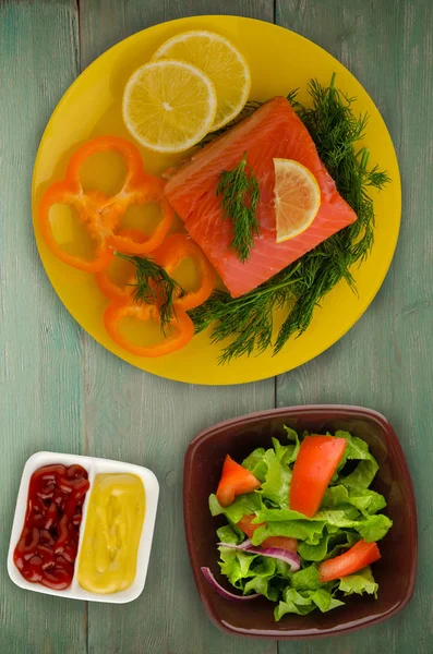 red fish trout fillets on a plate. fish trout on a wooden background. trout with dill, lemon and pepper