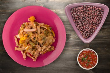 Ahşap arka plan üzerinde bir tabakta Berlin salata. Salata sosis, salatalık, biber üstten görünüm .
