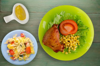 salata, Mısır ve domates bir tabakta tavuk kanadı. rustik bir arka plan üzerine Sebzeli tavuk kanadı