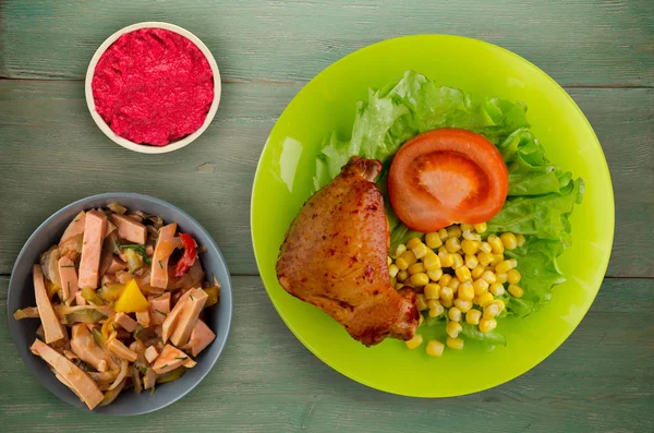 chicken wing with salad, corn and tomato on a plate. chicken wing with vegetables on a rustic background