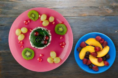 tatlı kek ve meyve (üzüm, kivi, nar) ahşap arka plan üzerinde. tatlı bir plaka Üstten Görünüm