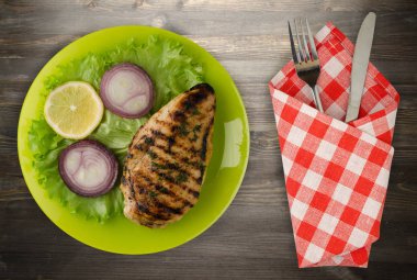  ahşap arka plan üzerinde (limon, salata, soğan) sebzeli ızgara tavuk fileto. bir plaka üstten görünüm üzerinde ızgara tavuk fileto