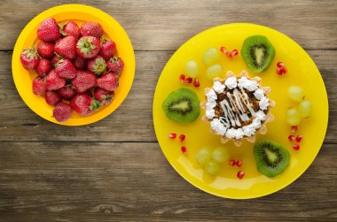 tatlı kek ve meyve (üzüm, kivi, nar) ahşap arka plan üzerinde. tatlı bir plaka Üstten Görünüm