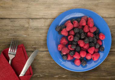 böğürtlen ve ahududu bir plaka üzerinde. böğürtlen ve ahududu ahşap arka plan üzerinde. Vejetaryen gıda .