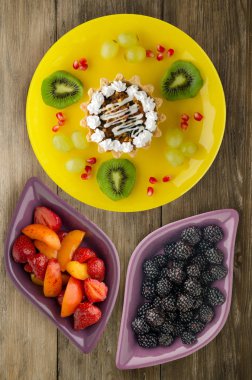 tatlı kek ve meyve (üzüm, kivi, nar) ahşap arka plan üzerinde. tatlı bir plaka Üstten Görünüm