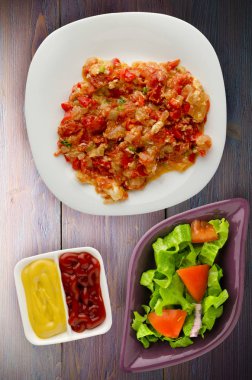 Haşlanmış domates soğan bir plaka üzerinde bir ahşap arka plan ile. haşlanmış domates soğan en iyi manzaralı. Vejetaryen Gıda