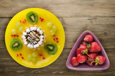 tatlı kek ve meyve (üzüm, kivi, nar) ahşap arka plan üzerinde. tatlı bir plaka Üstten Görünüm