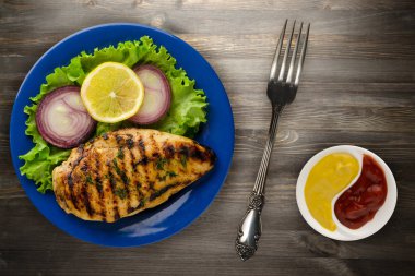  ahşap arka plan üzerinde (limon, salata, soğan) sebzeli ızgara tavuk fileto. bir plaka üstten görünüm üzerinde ızgara tavuk fileto