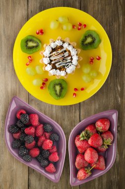 tatlı kek ve meyve (üzüm, kivi, nar) ahşap arka plan üzerinde. tatlı bir plaka Üstten Görünüm