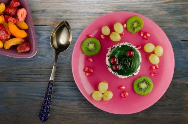 tatlı kek ve meyve (üzüm, kivi, nar) ahşap arka plan üzerinde. tatlı bir plaka Üstten Görünüm