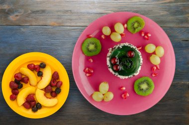 tatlı kek ve meyve (üzüm, kivi, nar) ahşap arka plan üzerinde. tatlı bir plaka Üstten Görünüm