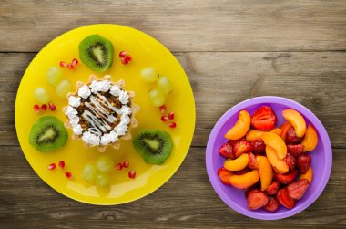 tatlı kek ve meyve (üzüm, kivi, nar) ahşap arka plan üzerinde. tatlı bir plaka Üstten Görünüm