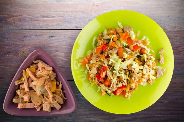 salad with chicken stomachs with vegetables (carrots, onions, peppers, cabbage, tomato, broccoli). salad with chicken on a plate on a wooden background