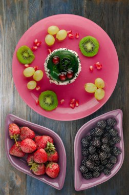 tatlı kek ve meyve (üzüm, kivi, nar) ahşap arka plan üzerinde. tatlı bir plaka Üstten Görünüm