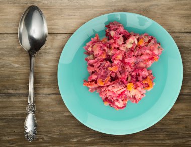 Ringa altında bir plaka üzerinde bir kürk manto. Bir kürk manto ahşap arka plan üzerinde altında ringa balığı. Ringa balığı, kırmızı pancar, havuç, mayonez ve soğan salata .