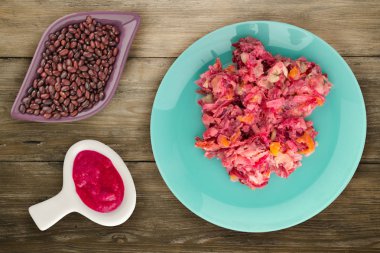 Ringa altında bir plaka üzerinde bir kürk manto. Bir kürk manto ahşap arka plan üzerinde altında ringa balığı. Ringa balığı, kırmızı pancar, havuç, mayonez ve soğan salata .