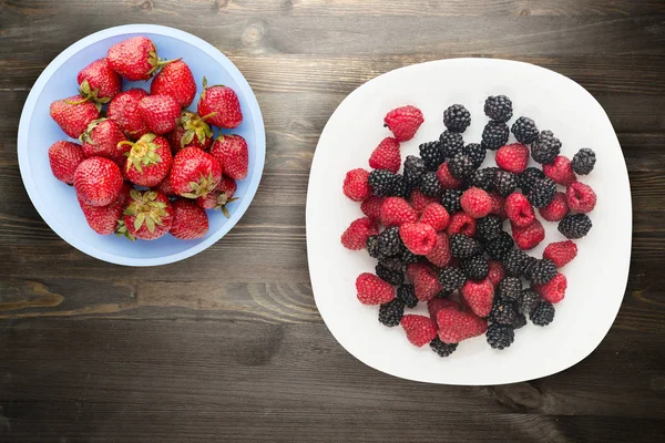 böğürtlen ve ahududu bir plaka üzerinde. böğürtlen ve ahududu ahşap arka plan üzerinde. Vejetaryen gıda .