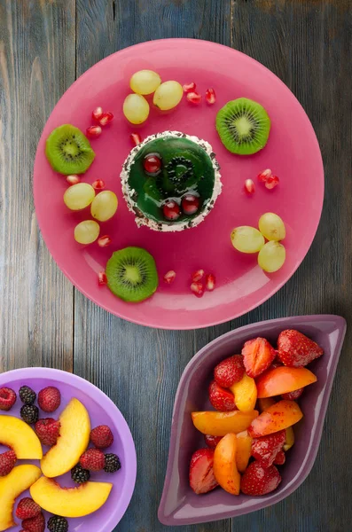 tatlı kek ve meyve (üzüm, kivi, nar) ahşap arka plan üzerinde. tatlı bir plaka Üstten Görünüm