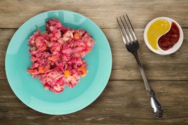 Ringa altında bir plaka üzerinde bir kürk manto. Bir kürk manto ahşap arka plan üzerinde altında ringa balığı. Ringa balığı, kırmızı pancar, havuç, mayonez ve soğan salata .