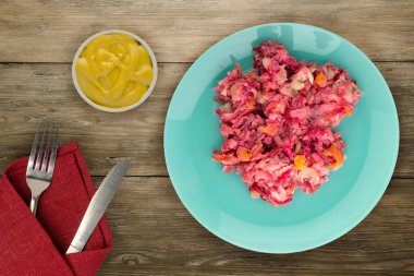 Ringa altında bir plaka üzerinde bir kürk manto. Bir kürk manto ahşap arka plan üzerinde altında ringa balığı. Ringa balığı, kırmızı pancar, havuç, mayonez ve soğan salata .