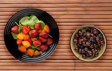 Vejetaryen gıda. sağlıklı gıda. bir salata, ıspanak, kayısı, çilek ahşap arka plan üzerinde bir plaka üzerinde.