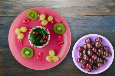 tatlı kek ve meyve (üzüm, kivi, nar) ahşap arka plan üzerinde. tatlı bir plaka Üstten Görünüm