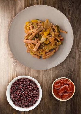 Ahşap arka plan üzerinde bir tabakta Berlin salata. Salata sosis, salatalık, biber üstten görünüm .