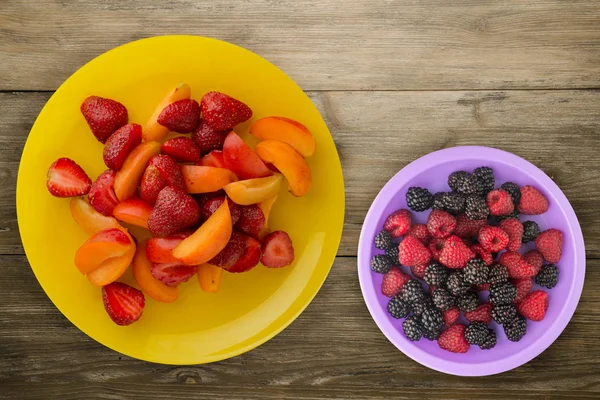 Comida saludable. Fresas y albaricoques en un plato. Frutos sobre fondo de madera — Foto de Stock
