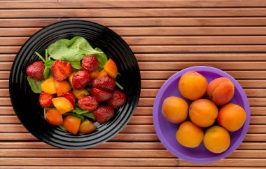 Vejetaryen gıda. sağlıklı gıda. bir salata, ıspanak, kayısı, çilek ahşap arka plan üzerinde bir plaka üzerinde 