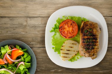  domuz eti, ahşap bir arka planda patates ve domates ile ızgara. bir plaka üzerinde ızgara domuz 