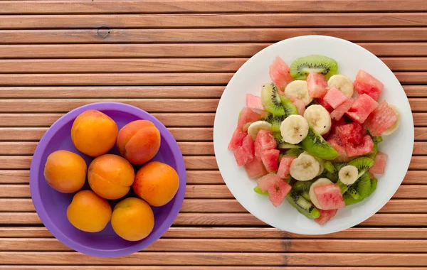 Teller mit gesundem frischem Obstsalat auf Holzgrund — Stockfoto