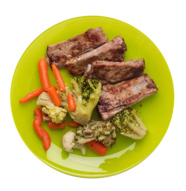 brokoli lahana, havuç ve sarımsak ile ızgara domuz kaburga bir tabakta. beyaz bir arka plan üzerinde sebze ile kızarmış kaburga. doyurucu rustik gıda üst görünümü