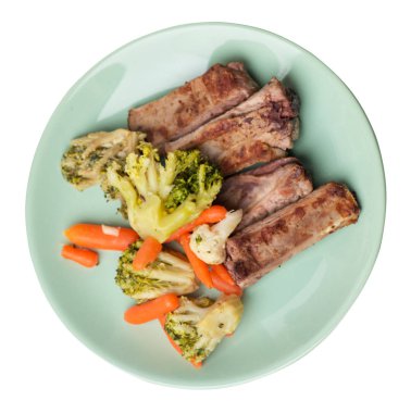 brokoli lahana, havuç ve sarımsak ile ızgara domuz kaburga bir tabakta. beyaz bir arka plan üzerinde sebze ile kızarmış kaburga. doyurucu rustik gıda üst görünümü