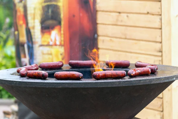 cooking sausages on fire. grilled sausages on metal chafing dish