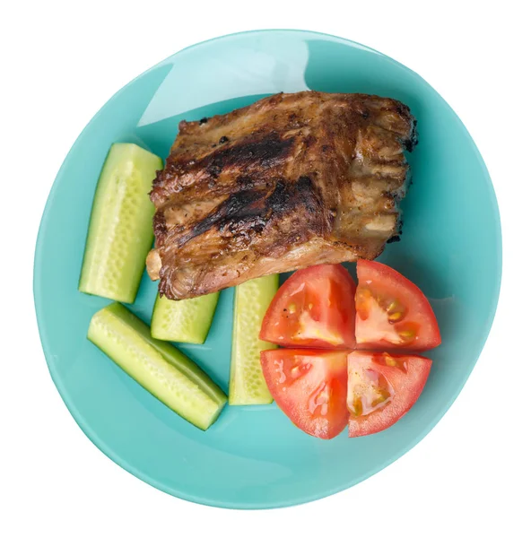 grilled pork ribs with sliced cucumbers and tomatoes on a plate. pork ribs isolated on white background. ribs  top view