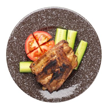 bir plaka üzerinde dilimlenmiş salatalık ve domates ile ızgara domuz kaburga.