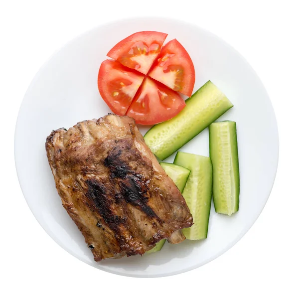 grilled pork ribs with sliced cucumbers and tomatoes on a plate.