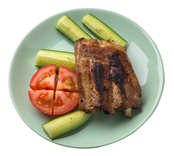 grilled pork ribs with sliced cucumbers and tomatoes on a   pla