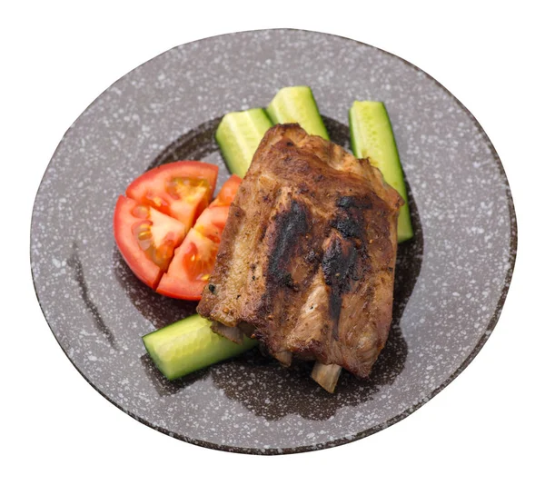 grilled pork ribs with sliced cucumbers and tomatoes on a   pla